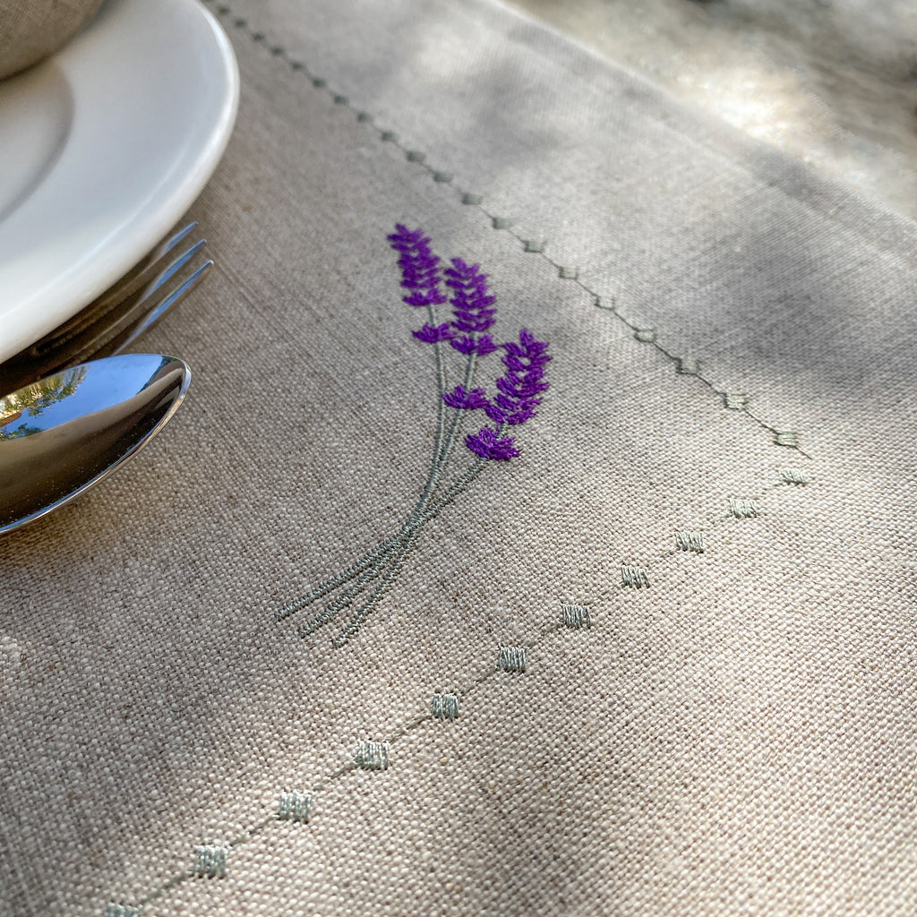 Abwaschbares Tischset aus beigem Leinen mit fein gestickten Lavendelmustern.