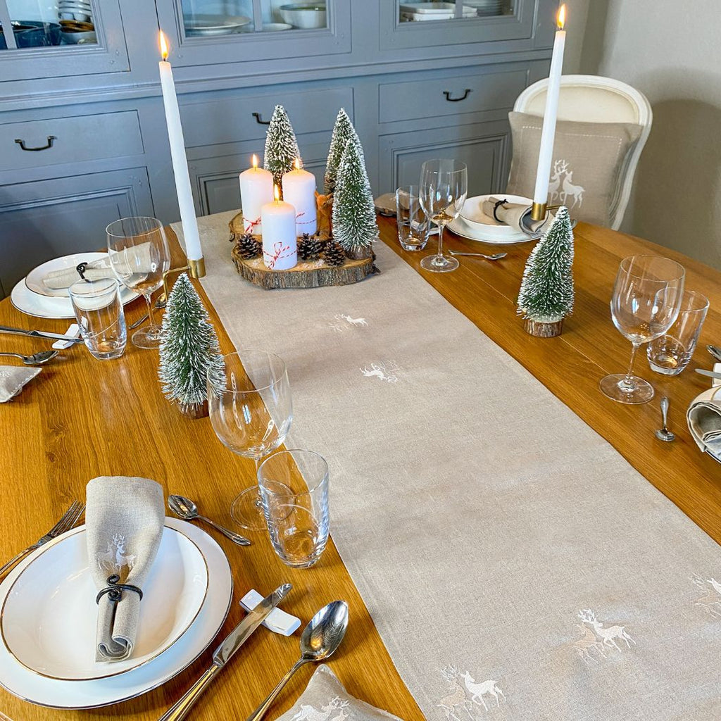 Suchen Sie einen Tischläufer aus Leinen für Ihren Weihnachtstisch? Auf dem Foto sehen Sie einen Tischläufer aus beigem Leinen mit einem zart gestickten Hirschmotiv.
