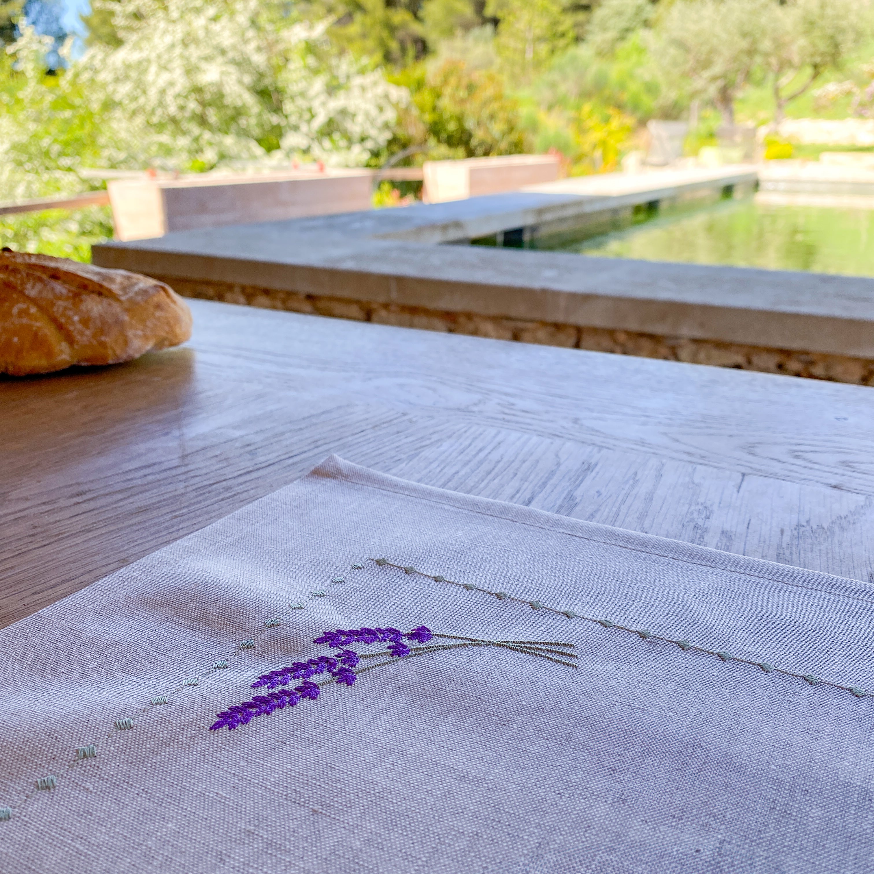 Tischset aus beschichtetem Leinen mit feiner Lavendelstickerei, handgefertigt in unseren Werkstätten in Südfrankreich. Abgebildet auf einem gedeckten Tisch – pflegeleicht und stilvoll für mediterrane Tischkultur.