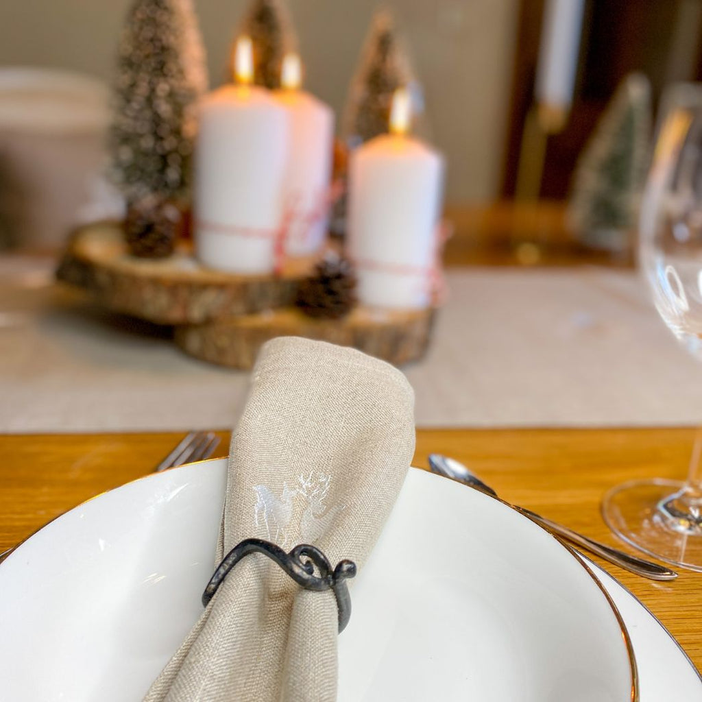 Suchen Sie schöne Leinenservietten für Weihnachten? Auf diesem Foto ist es eine beige Leinenserviette mit einem schönen Hirschmuster. Perfekt für einen Weihnachtstisch mit rustikalem Charme und hochwertigem Material.